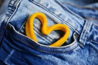 Foto eine Jeans mit einem Herz aus einem gelben Schnürsenkel